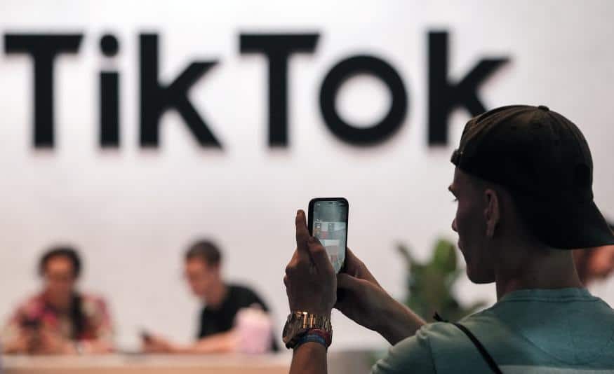 Person using phone with TikTok Text in the background.